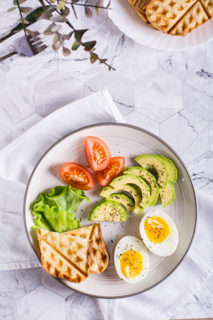 Avocado, soft boiled egg, tomatoes, lettuce and toast on a plate. Healthy food. Top and vertical